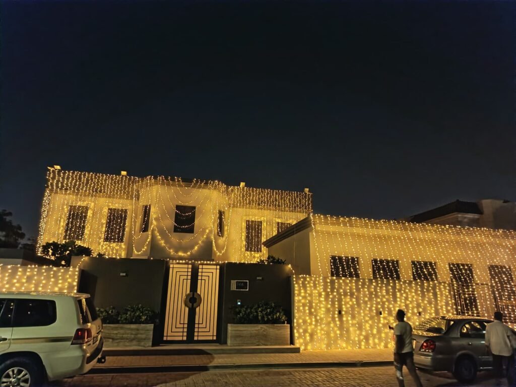 front view of a home covered in golden led curtain lights, creating a festive and elegant night time lighting display.