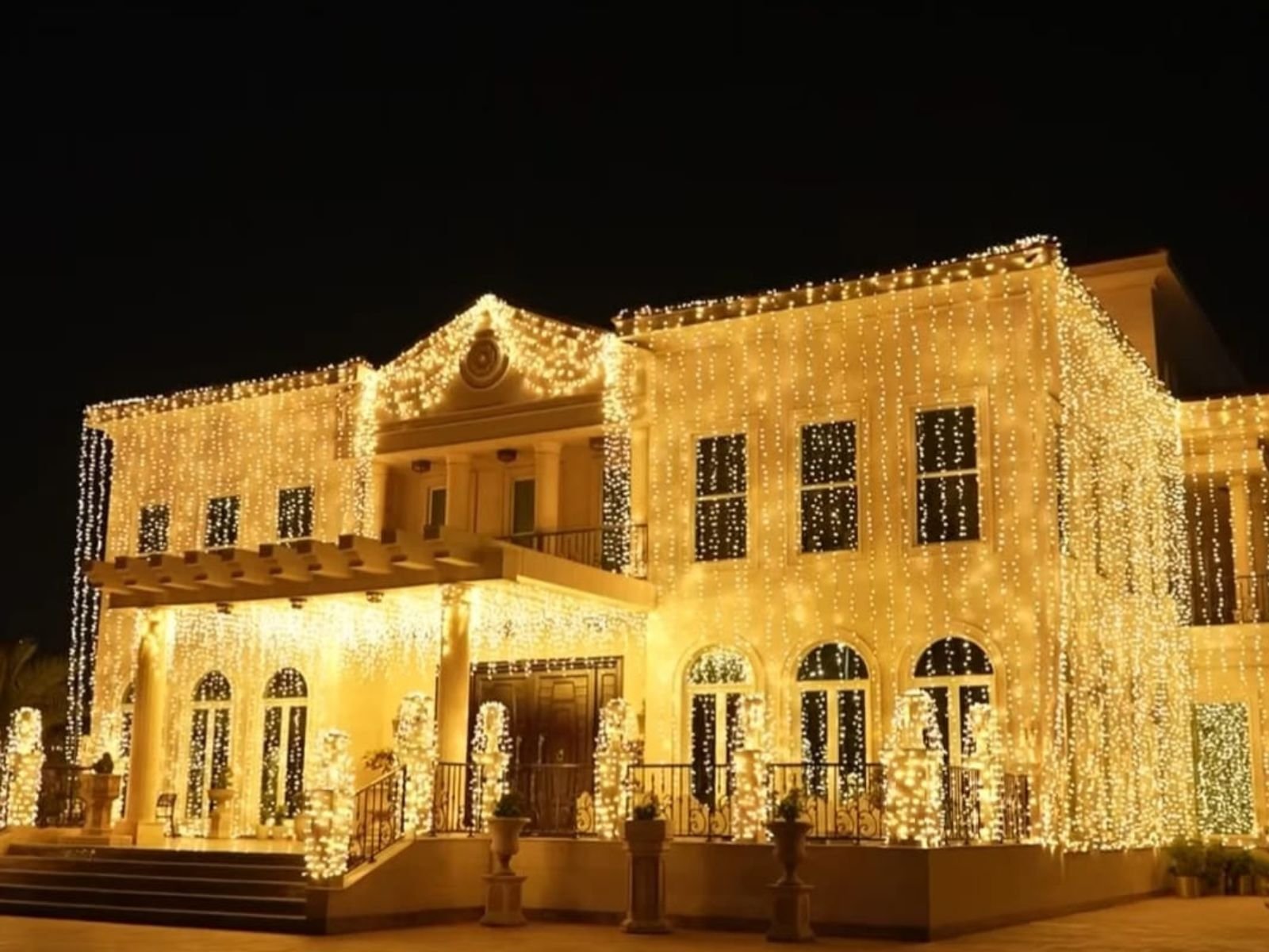 Home luxury wedding lighting decoration for a private villa in qatar with warm golden fairy lights illuminating the exterior facade at nigh