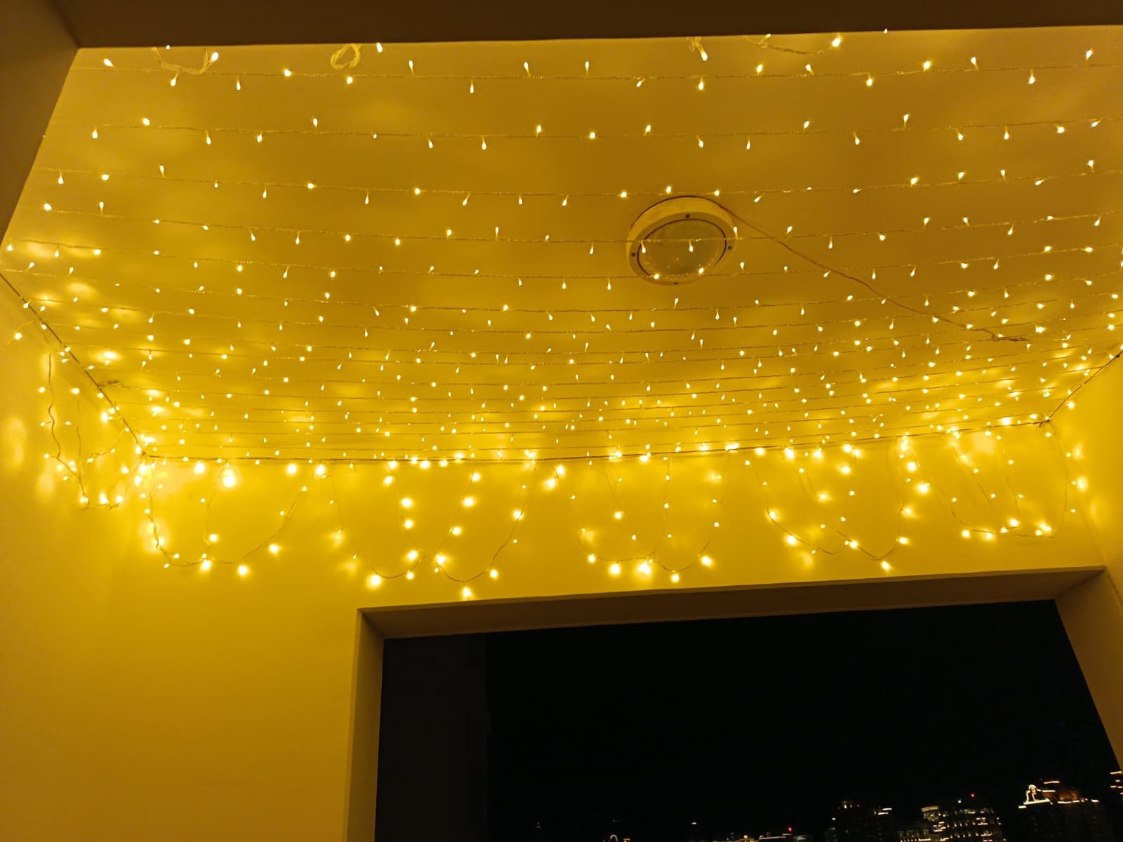 Home romantic wedding balcony lighting using warm white string lights, enhancing evening wedding décor with a modern city backdrop in qatar.