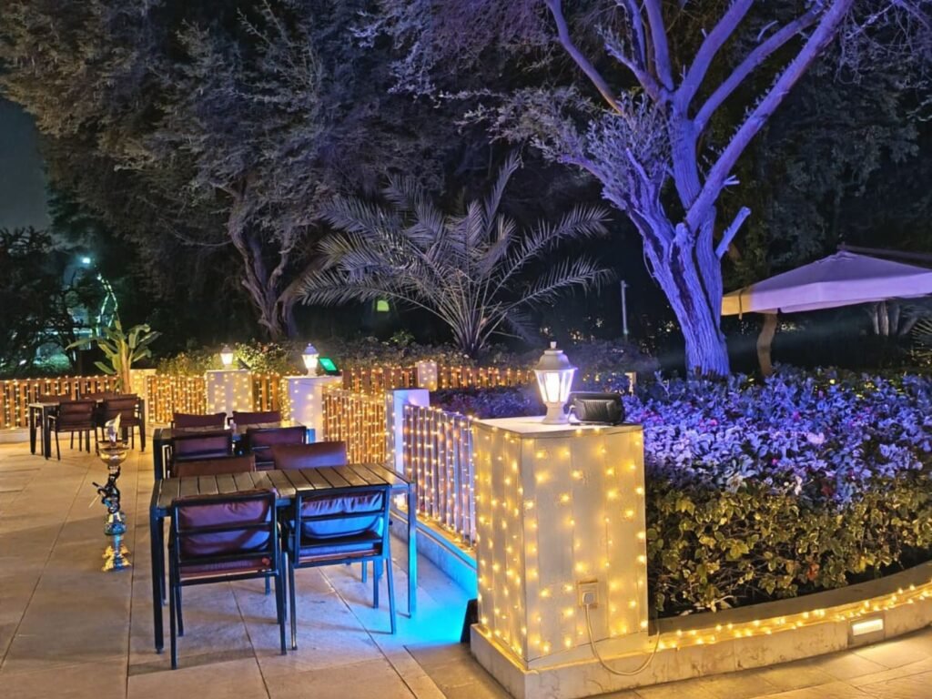 outdoor terrace seating area decorated with warm white fairy lights along railings and garden walls at night